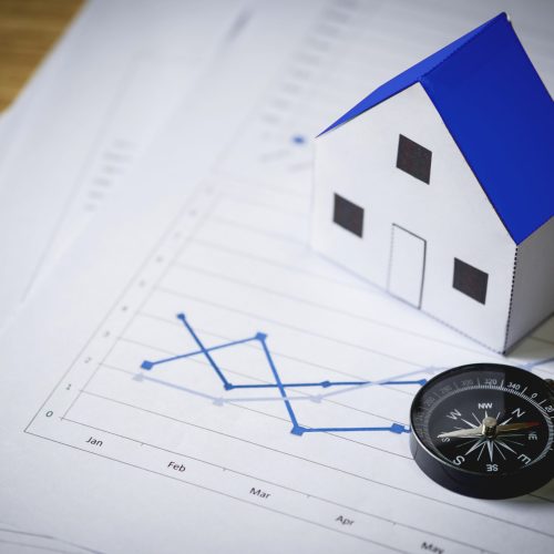House model and compass on plan background, Real estate concept.